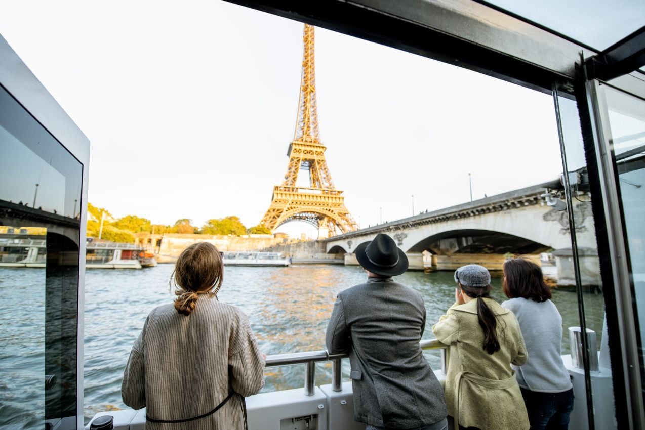 Des personnes admirant la magnifique vue sur les berges et la tour Eiffel depuis un bateau, au coucher du soleil à Paris