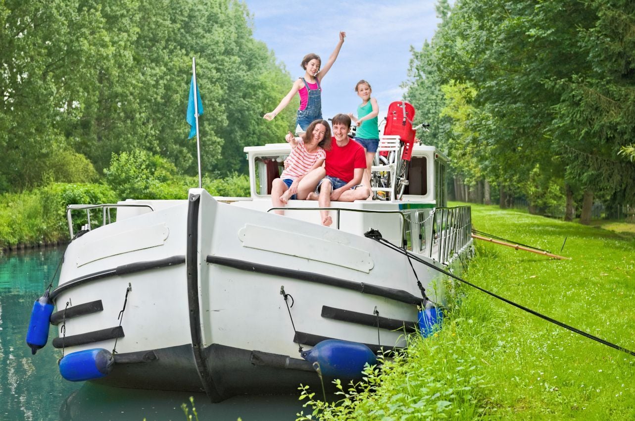des enfants ravis et des parents qui s'amusent lors d'une croisière fluviale et estival à bord d'une péniche sur des canaux de France